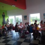 Wakacje z biblioteką - akcja dla dzieci - dzieci siedzące przy stolikach podczas posiłku