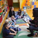 Spotkania dzieci z biblioteką - dzieci siedzą na podłodze i słuchają czytanej im bajce
