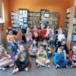 Spotkania dzieci z biblioteką - dzieci siedzą na krzesełkach i poduszkach śpiewając piosenki