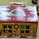 Tekturowy domek świątecznie przyozdobiony i z dachem obsypanym śniegiem