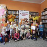 Zdjęcie grupowe dzieci w bibliotece z wielkimi pluszowymi maskotkami Kubusia Puchatka i Tygryska