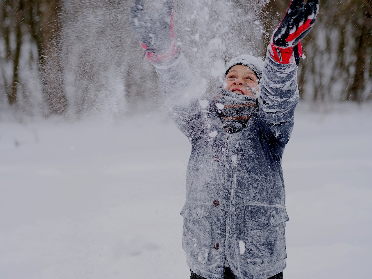 Dziecko ciepło ubrane w śnieżny dzień rzucające w górę śnieg. Image by Amr from Pixabay