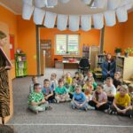 Spotkanie autorskie - dzieci siedzą na podłodze i uważnie słuchają czytanego przez rodziców opowiadania