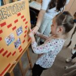 Dzieci wykonują pamiątkowe plansze, na których oprócz zdjęć grupowych przyklejają czerwone karteczki ze swoimi imionami