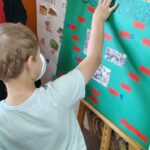 Dzieci wykonują pamiątkowe plansze, na których oprócz zdjęć grupowych przyklejają czerwone karteczki ze swoimi imionami