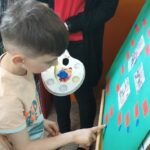 Dzieci wykonują pamiątkowe plansze, na których oprócz zdjęć grupowych przyklejają czerwone karteczki ze swoimi imionami