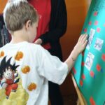 Dzieci wykonują pamiątkowe plansze, na których oprócz zdjęć grupowych przyklejają czerwone karteczki ze swoimi imionami