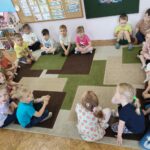 Dzieci siedzą w kółeczku na ziemi