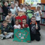 Zdjęcie grupowe dzieci z wykonaną wcześniej planszą pamiątkową