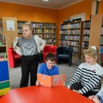 Dzieci przy czerwonym stole w sali biblioteki