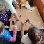 Dzieci przy stoliku wykonują prace plastyczne - papierowe pieski