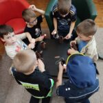 Dzieci przy stoliku wykonują prace plastyczne - papierowe pieski