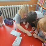 Dzieci przy czerwonym stoliku przygotowują pracę plastyczną