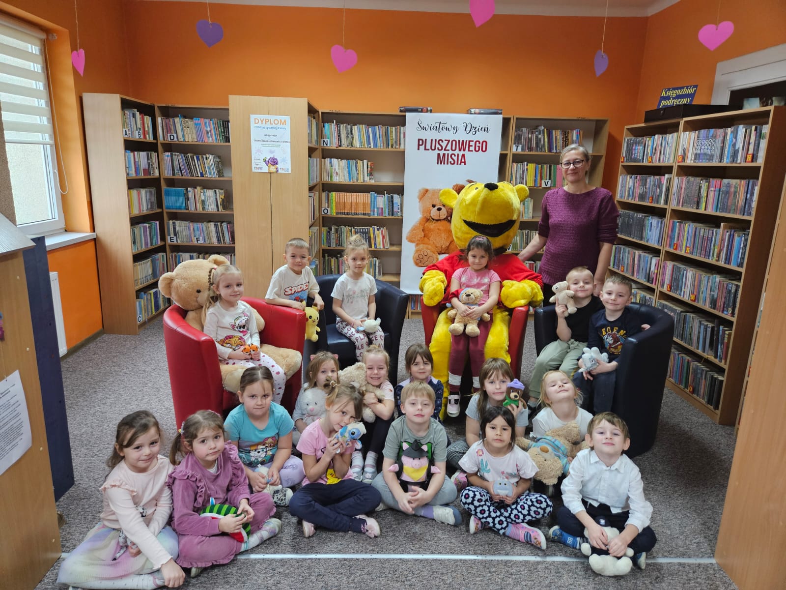 Dzień Pluszowego Misia w bibliotece - zdjęcie grupowe Kubusia Puchatka z uczestnikami spotkania