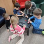 Dzieci przy stoliku wykonują pracę plastyczną - czarnego kota