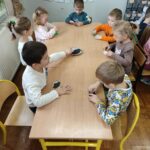 Dzieci siedzą przy stole i wykonują pracę plastyczną - jeżyki.