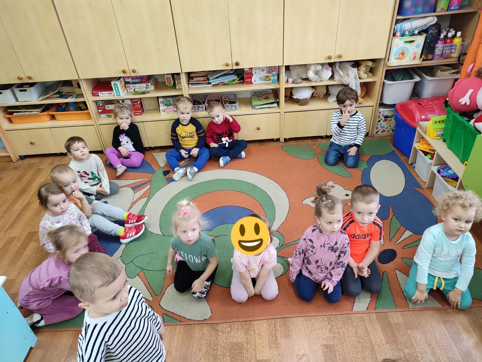 Dzieci siedzą na podłodze i z uwagą słuchają opowiadania