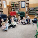 Dzieci siedzą na ziemi i z uwagą słuchają opowiadania