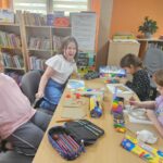 Dzieci przy stoliku wykonują pracę plastyczną