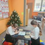 Dzieci przy stoliku wykonują pracę plastyczną