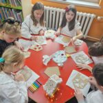 Dzieci przy stoliku wykonują pracę plastyczną
