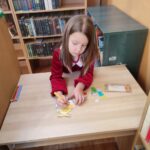 Dzieci przy stolikach wykoują pracę plastyczną