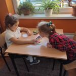 Dzieci przy stolikach wykoują pracę plastyczną