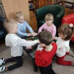 Dzieci przy stolikach wykoują pracę plastyczną