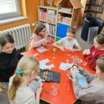 Dzieci przy stoliku wykonują pracę plastyczną