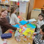 Dzieci przy stoliku wykonują pracę plastyczną