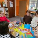 Dzieci przy stoliku wykonują pracę plastyczną