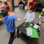 Dzieci przy stoliku wykonują pracę plastyczną