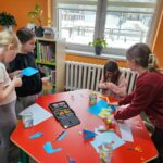Dzieci przy stoliku wykonują pracę plastyczną