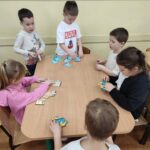 Dzieci przy stoliku wykonują pracę plastyczną