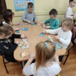 Dzieci przy stoliku wykonują pracę plastyczną