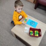 Chłopak przy stoliku wykonuje pracę plastyczną