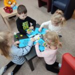 Dzieci przy stoliku wykonują pracę plastyczną