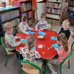 Dzieci przy stoliku wykonują pracę plastyczną