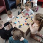 Dzieci przy stoliku wykonują pracę plastyczną