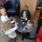 Dzieci przy stoliku wykonują pracę plastyczną