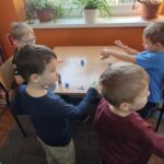 Dzieci przy stoliku wykonują pracę plastyczną