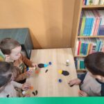 Dzieci przy stoliku wykonują pracę plastyczną