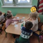 Dzieci siedzą przy stoliku i wykonują pracę plastyczną