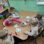 Dzieci siedzą przy stoliku i wykonują pracę plastyczną