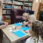 Dzieci przy stoliku wykonują pracę plastyczną
