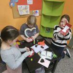 Dzieci przy stoliku wykonują pracę plastyczną