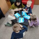Dzieci przy stoliku wykonują pracę plastyczną