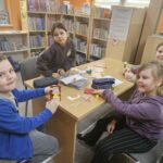 Dzieci przy stoliku wykonują pracę plastyczną