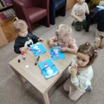 Dzieci przy stoliku wykonują pracę plastyczną