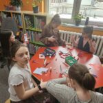 Dzieci przy stoliku wykonują pracę plastyczną